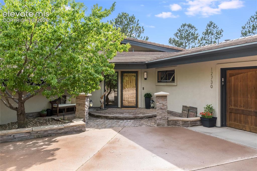Image 3 of 50: Front entrance featuring a rich wood door, stone facade accents, and a pave