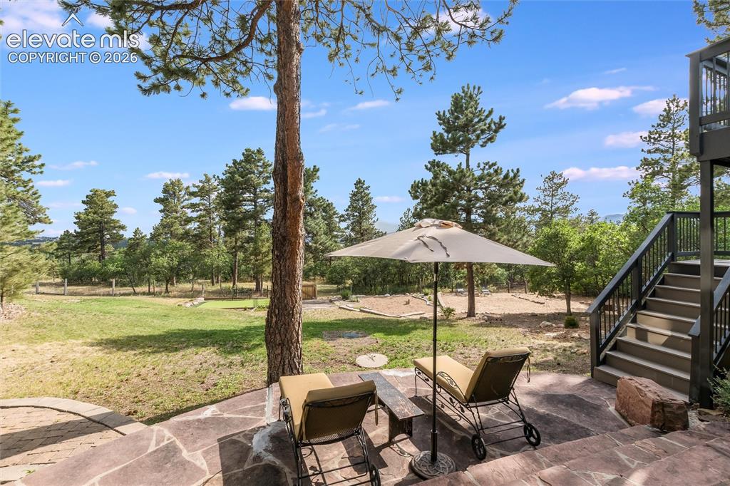 Image 32 of 50: Stone patio with irregular flagstone pavers, surrounded by mature trees and