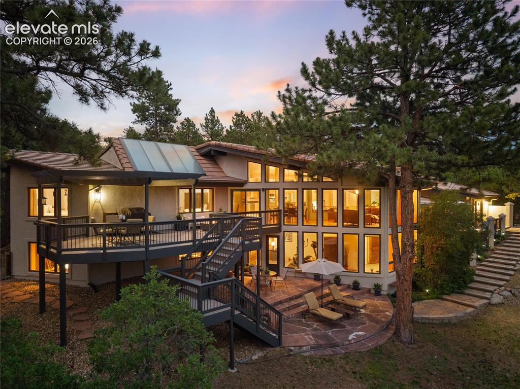 Image 43 of 50: Multi-level deck and patio area featuring a stone patio, extensive window a