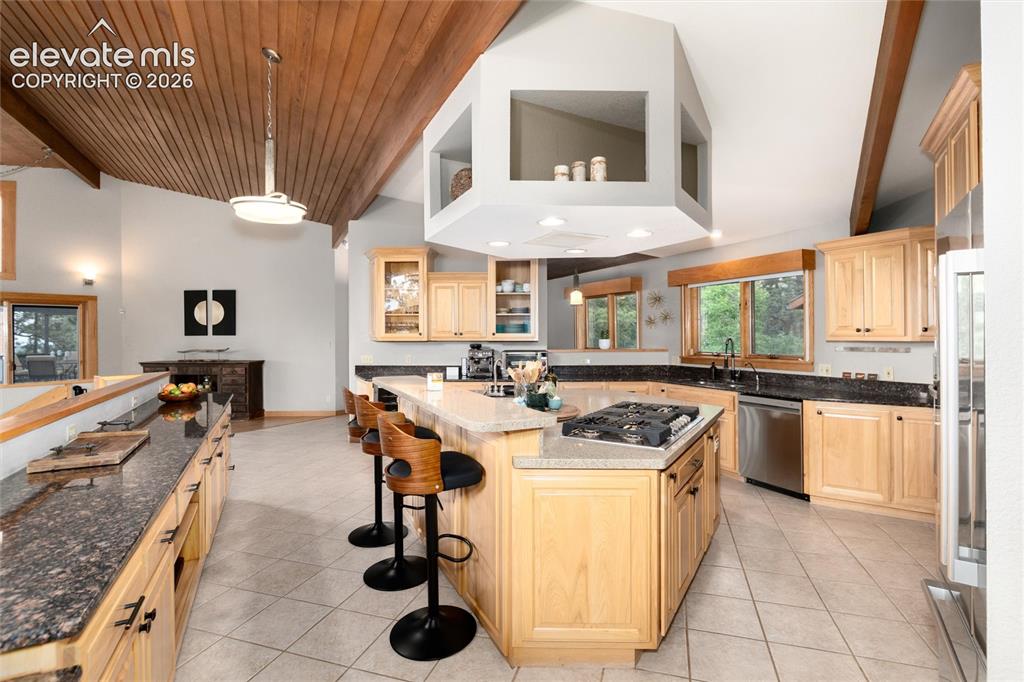 Image 7 of 50: Kitchen featuring a multi-level island with seating, a cooktop, and light w