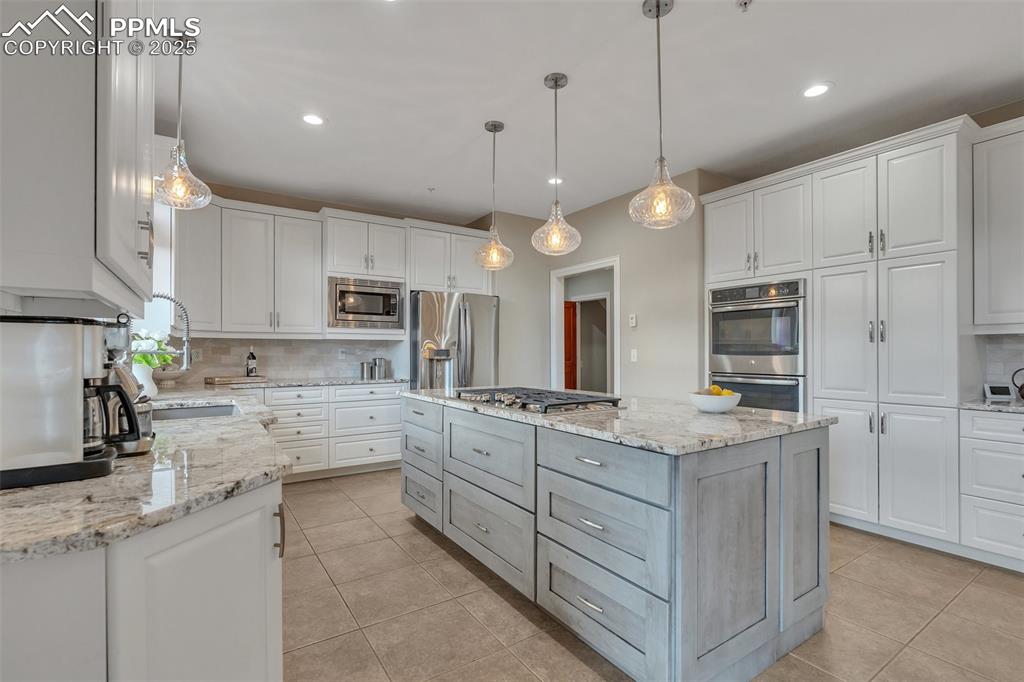 Image 2 of 49: Kitchen featuring appliances with stainless steel finishes, decorative back