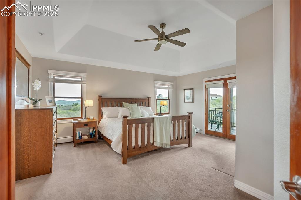 Image 22 of 49: Bedroom with a raised ceiling, access to exterior, multiple windows, and ca