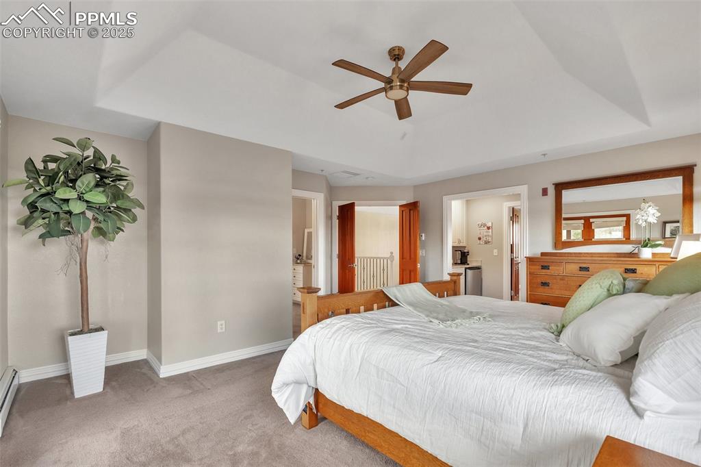 Image 24 of 49: Carpeted bedroom with baseboards, a baseboard heating unit, a tray ceiling,