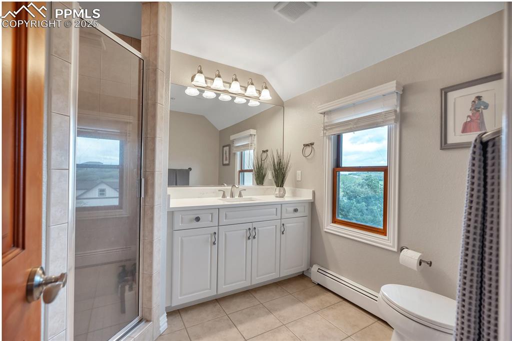 Image 30 of 49: Bathroom with lofted ceiling, a baseboard heating unit, tile patterned floo