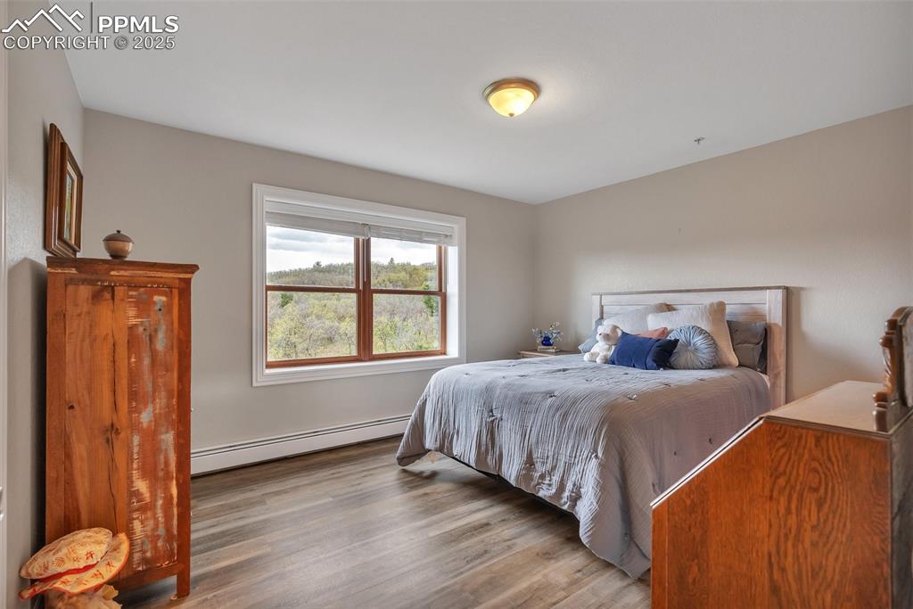 Image 31 of 49: Bedroom featuring baseboard heating and wood finished floors
