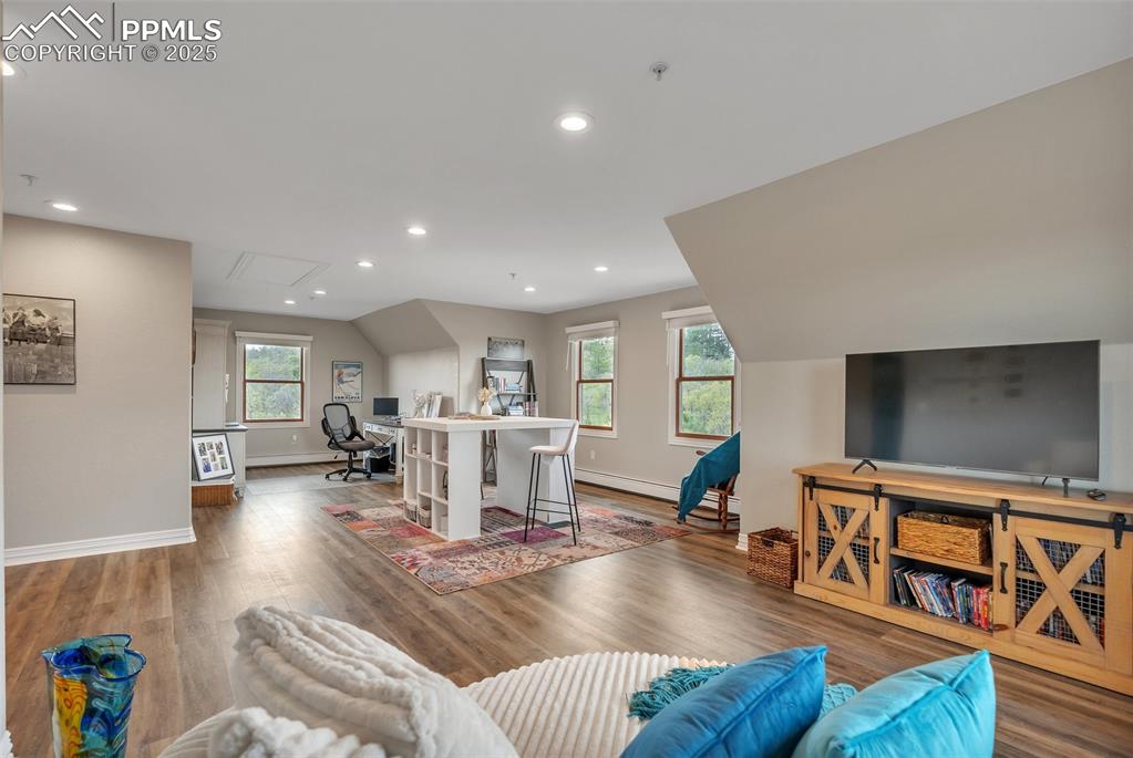 Image 33 of 49: Living room with baseboards, wood finished floors, recessed lighting, attic