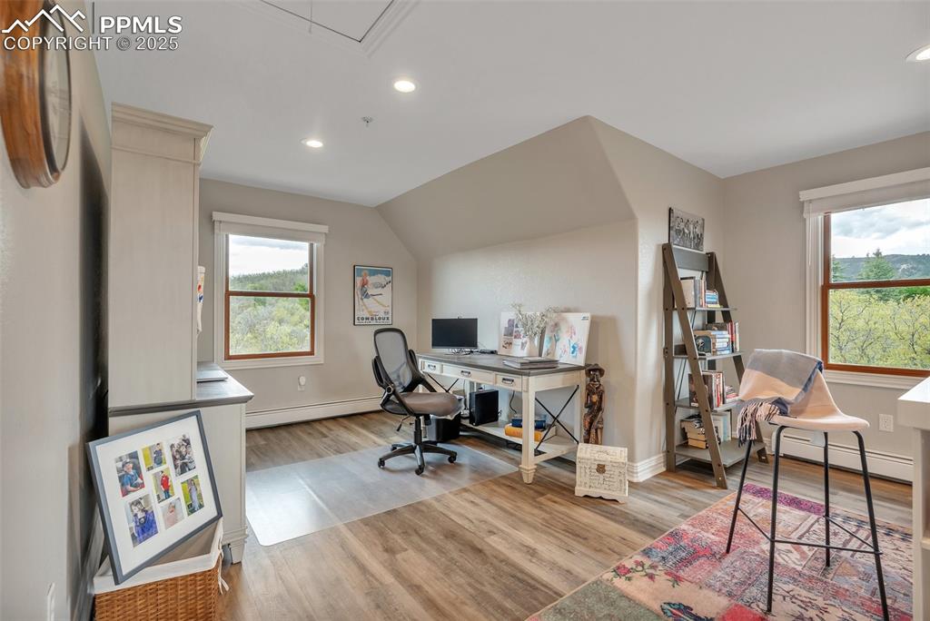 Image 36 of 49: Office area with a baseboard heating unit, wood finished floors, recessed l