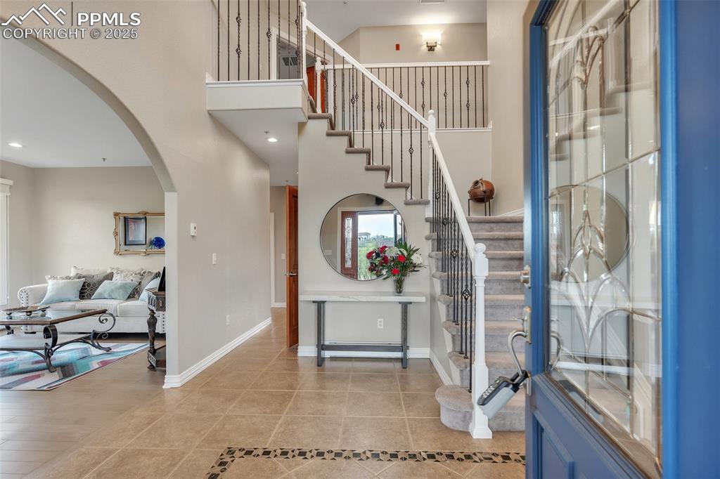 Image 4 of 49: Foyer featuring arched walkways, tile patterned floors, stairway, a towerin