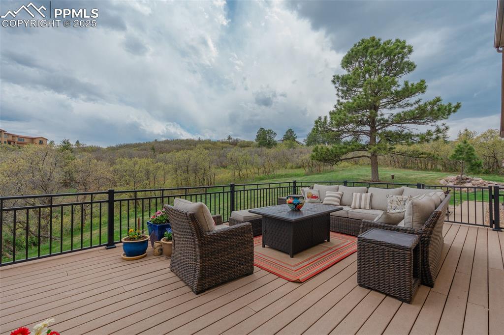Image 40 of 49: Wooden terrace with an outdoor hangout area and a view of trees