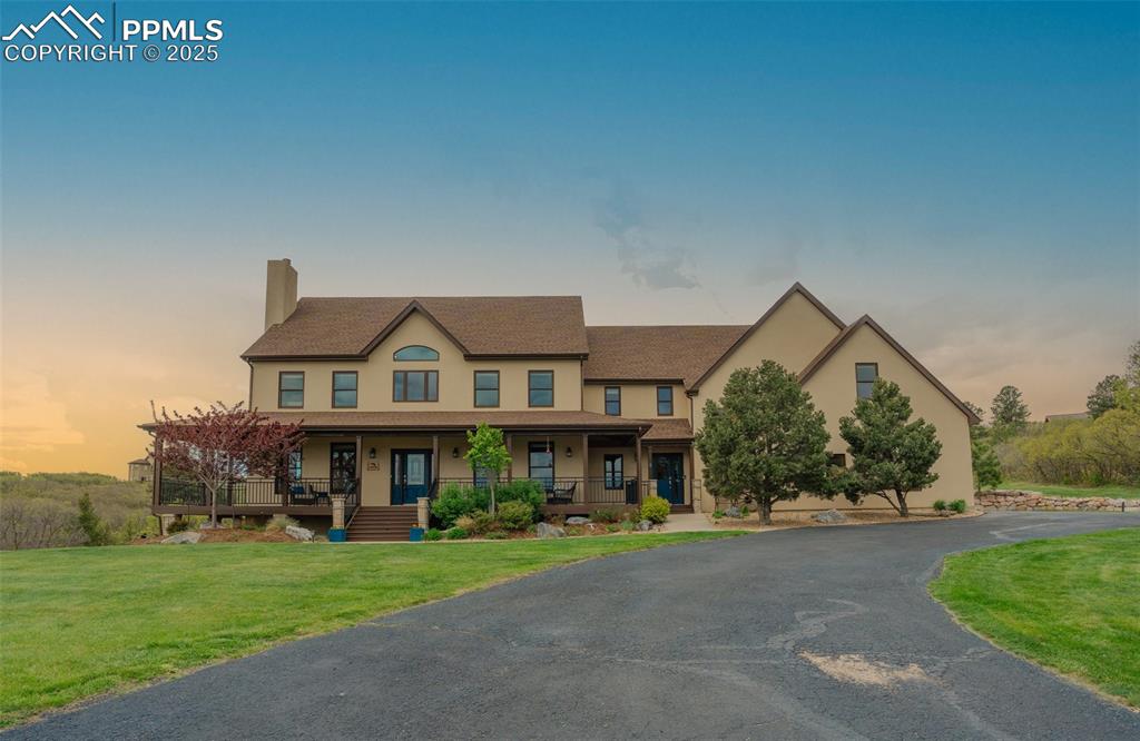Image 42 of 49: View of property featuring a chimney, a porch, a front lawn, and stucco sid