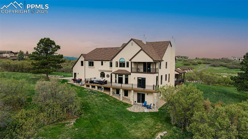 Image 43 of 49: Back of house at dusk featuring a balcony, stucco siding, a patio area, and