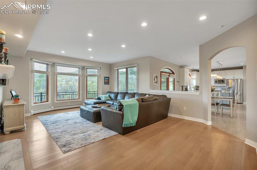 Image 5 of 49: Living area with baseboard heating, arched walkways, light wood-style floor