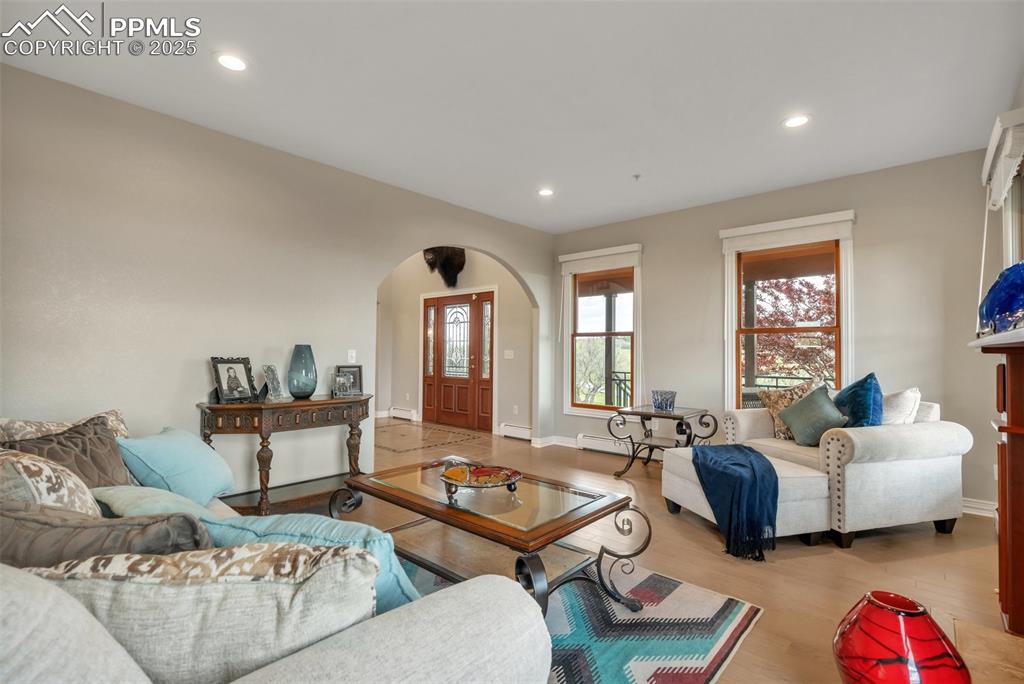 Image 7 of 49: Living area featuring arched walkways, wood finished floors, baseboards, re