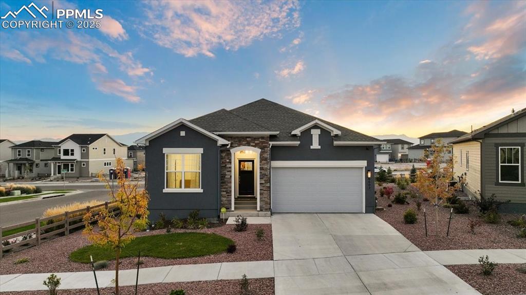 Caption: View of front facade featuring stucco siding, stone siding, concrete driveway, an attached garage, a