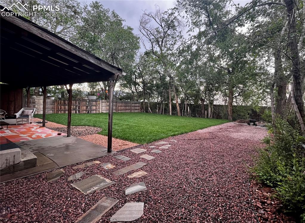 Image 23 of 28: Backyard during the summer, trees full of foliage and lush green grass