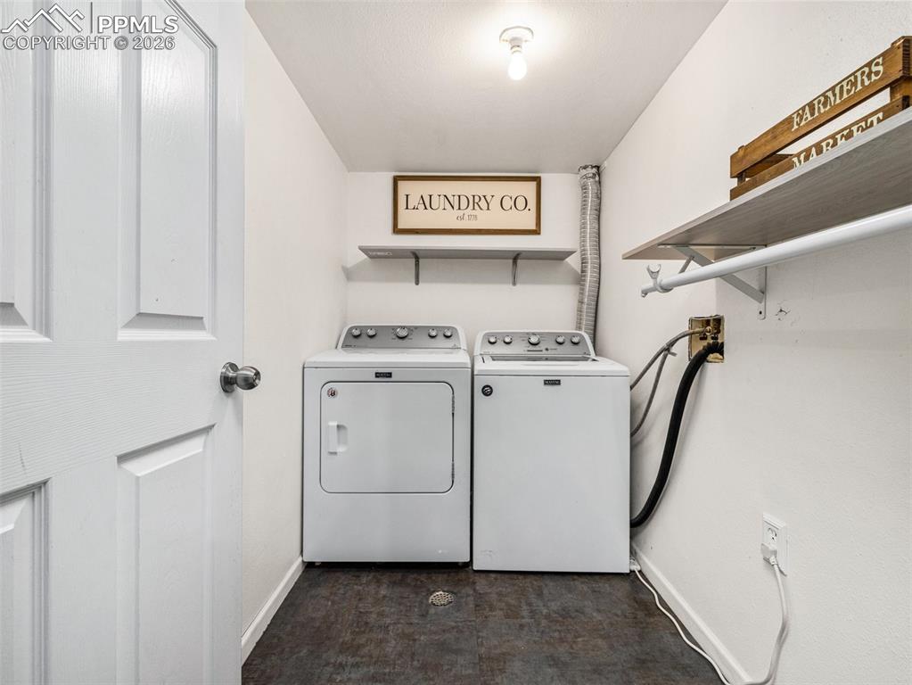 Image 23 of 31: Washroom featuring washing machine and clothes dryer and dark floors