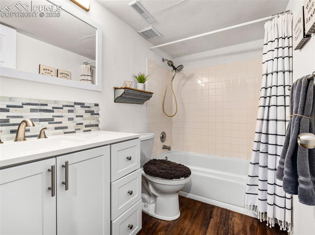 Image 24 of 31: Bathroom featuring vanity, shower / bathtub combination with curtain, dark 