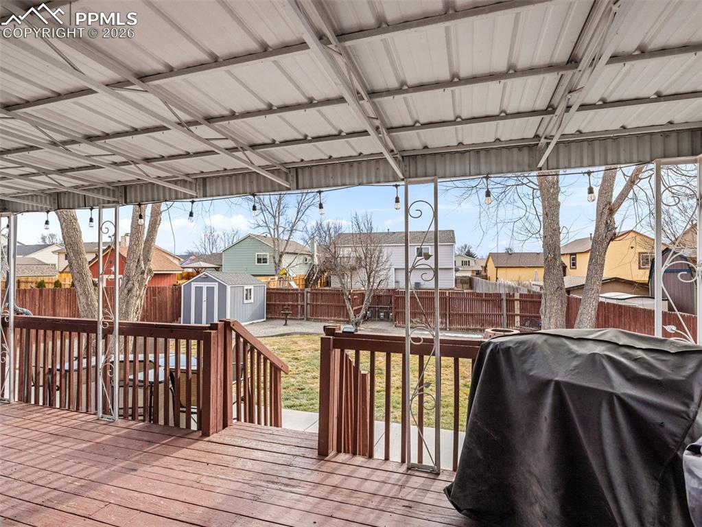 Image 27 of 31: Wooden terrace with a residential view, a storage shed, a grill, and a fenc