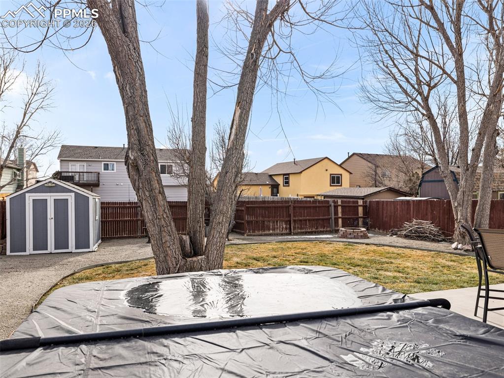 Image 28 of 31: Fenced backyard featuring a residential view, a storage unit, hot tub