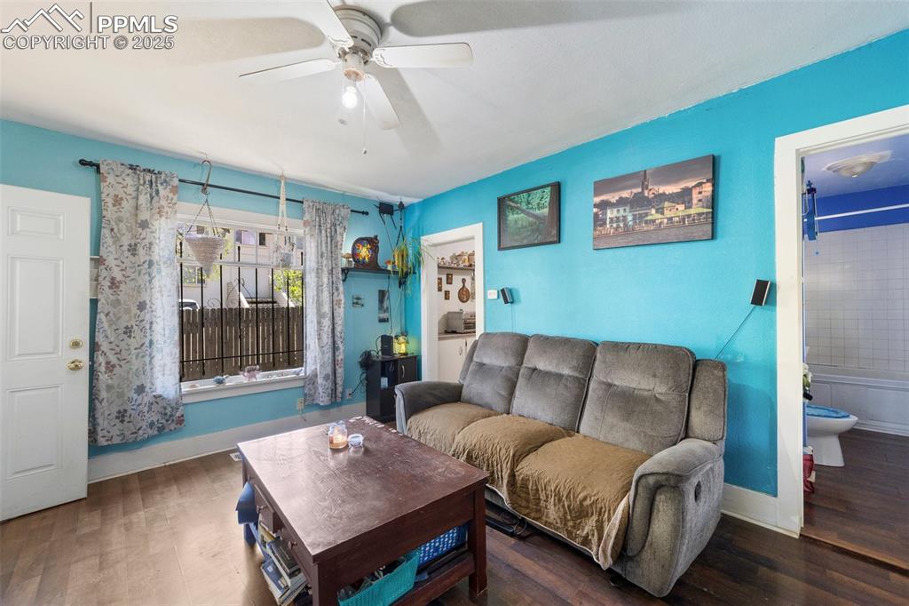 Image 29 of 31: Living area with a ceiling fan, wood finished floors, and baseboards