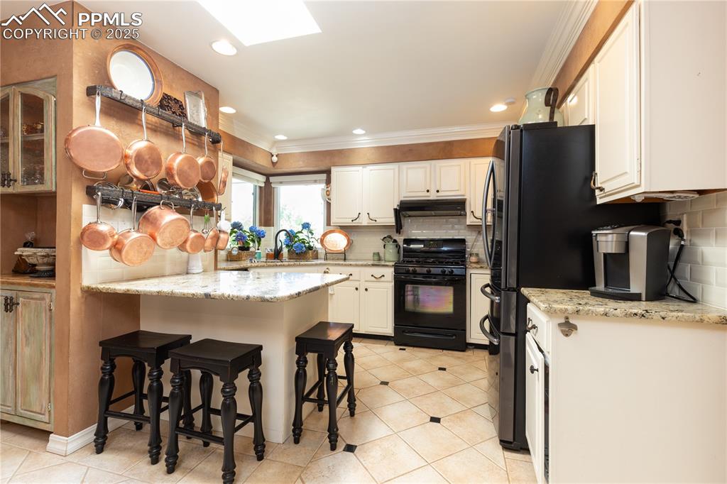 Image 10 of 49: Granite countertops in the bright kitchen with a great view above the sink