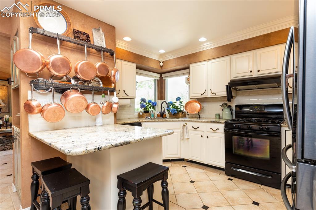 Image 11 of 49: Granite breakfast bar and counters, gas range/oven, corner sink to watch th