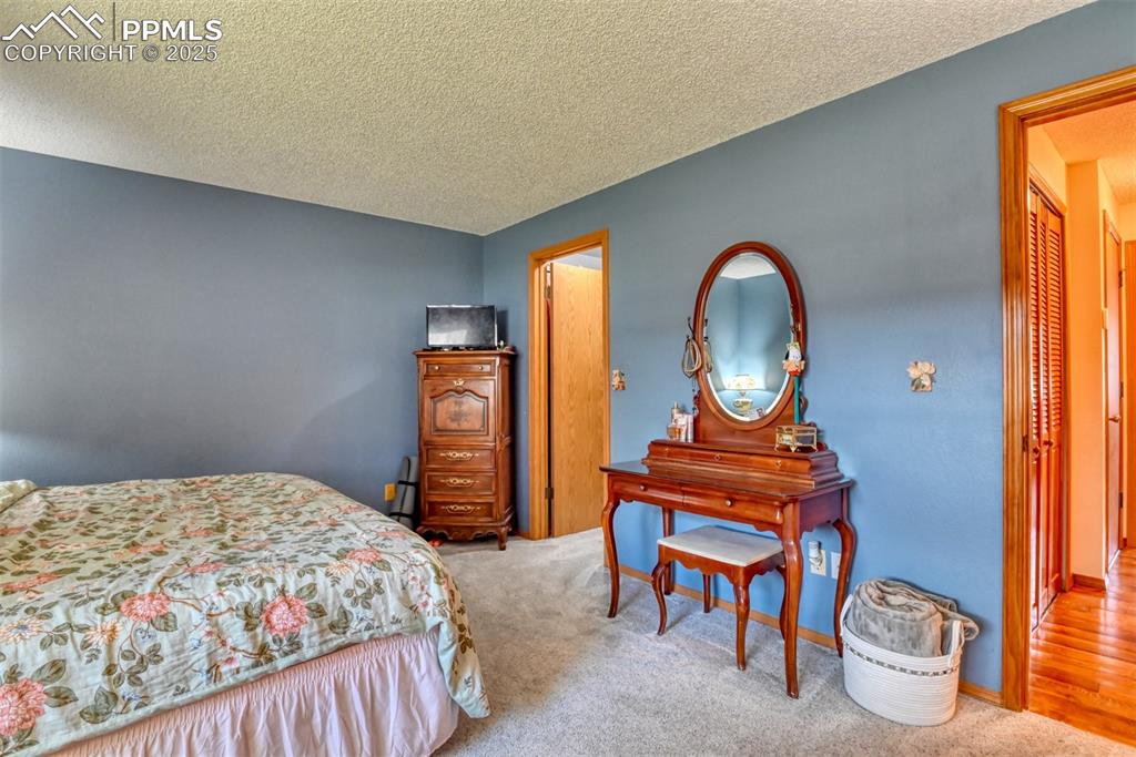Image 14 of 32: Carpeted bedroom with a textured ceiling and baseboards