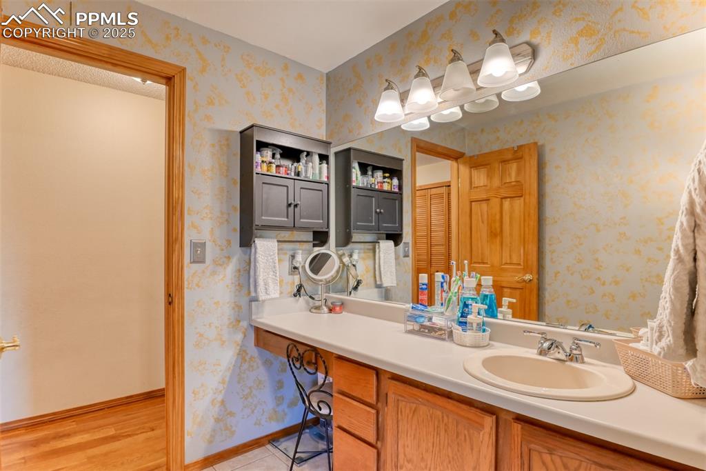 Image 16 of 32: Bathroom featuring wallpapered walls, vanity, and wood finished floors