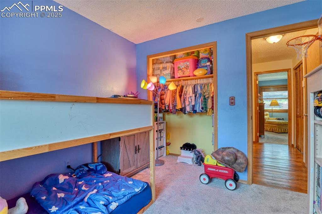 Image 20 of 32: Bedroom with a textured ceiling, carpet flooring, and a closet