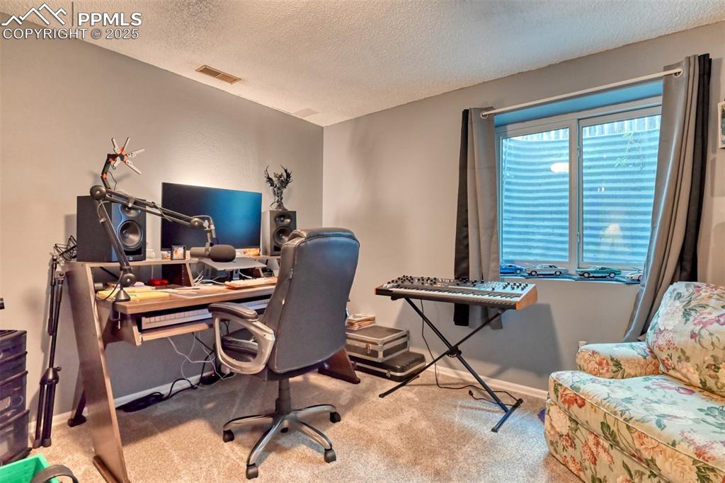 Image 25 of 32: Home office with a textured ceiling and carpet flooring