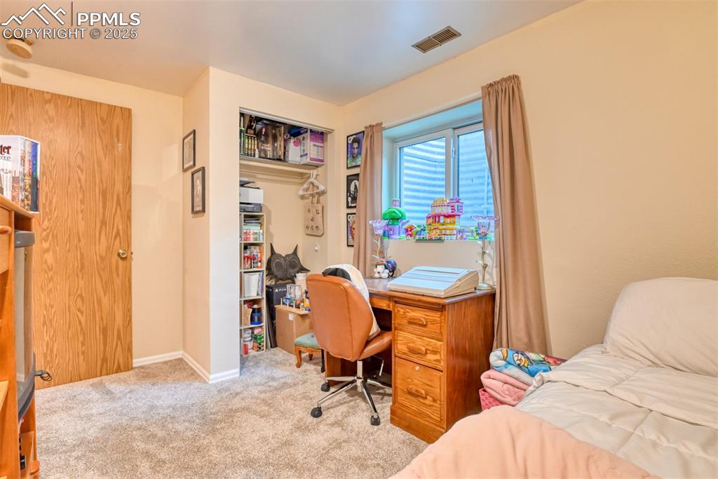 Image 27 of 32: Carpeted bedroom with an office area and a closet