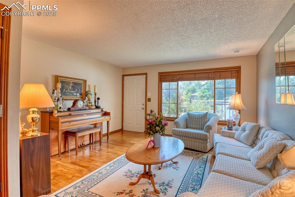 Image 3 of 32: Living area featuring light wood-type flooring and a textured ceiling