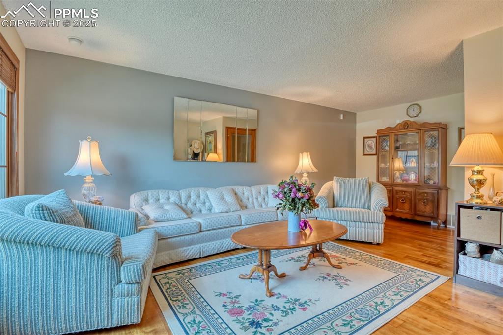 Image 5 of 32: Living area with wood finished floors and a textured ceiling