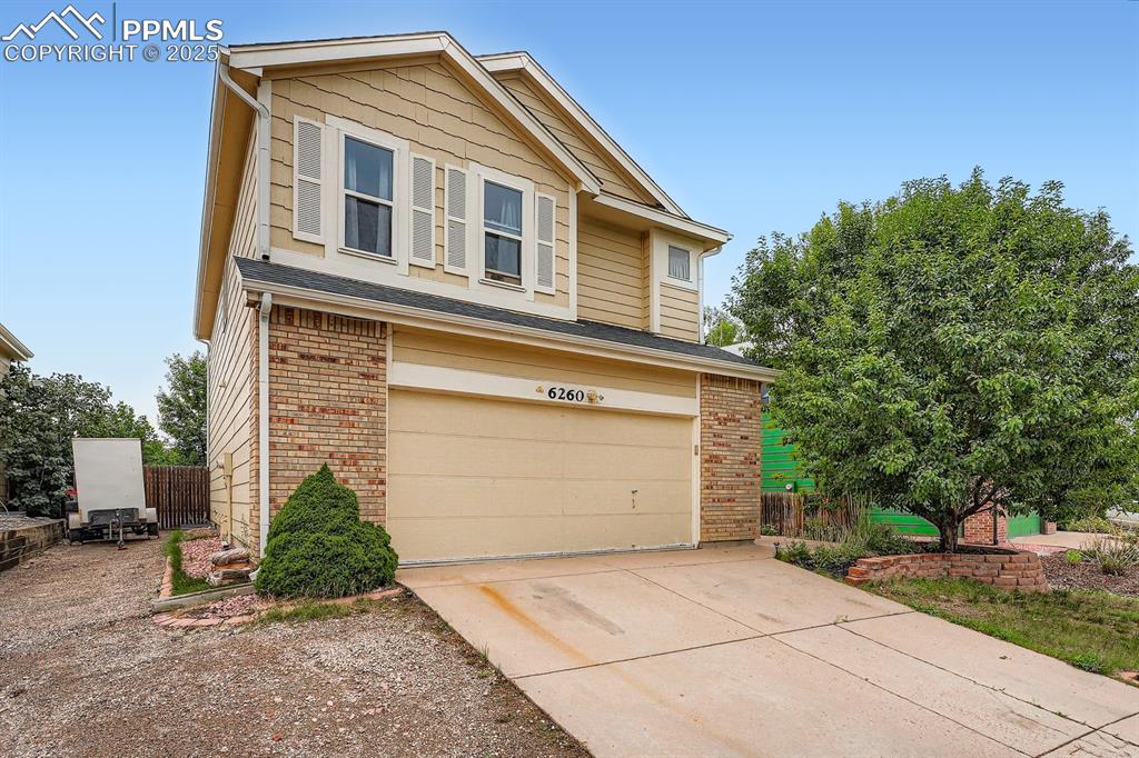 Caption: Traditional-style house featuring brick siding, driveway, and a garage