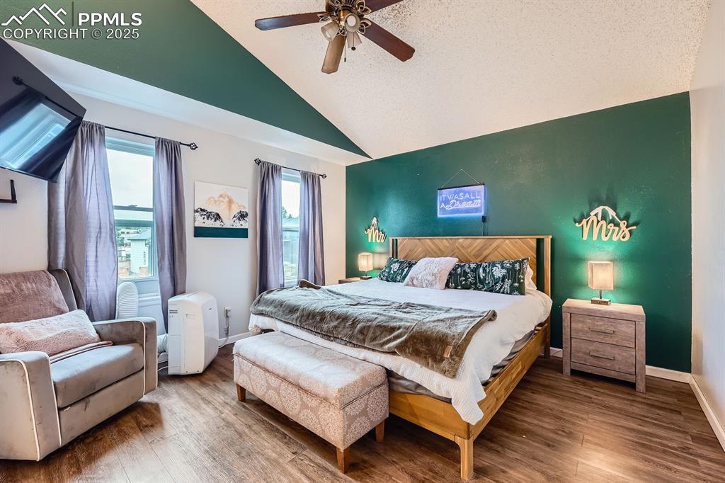 Image 11 of 28: Bedroom featuring wood finished floors, high vaulted ceiling, and a ceiling