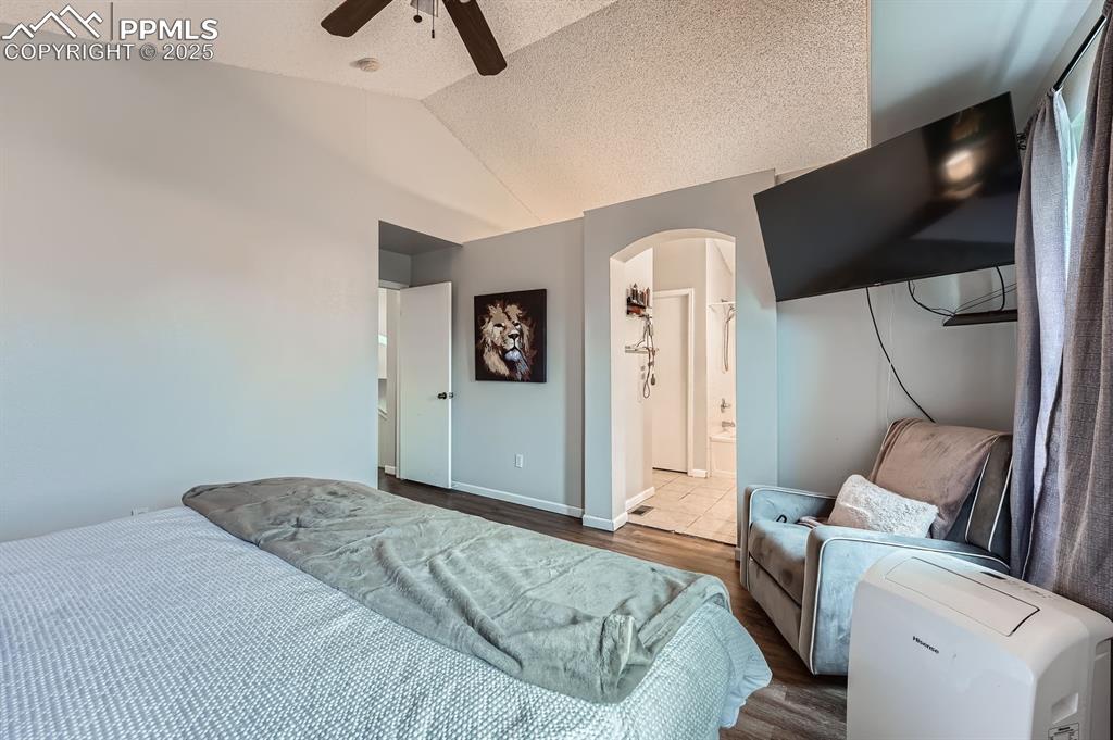 Image 12 of 28: Bedroom with arched walkways, lofted ceiling, wood finished floors, ceiling