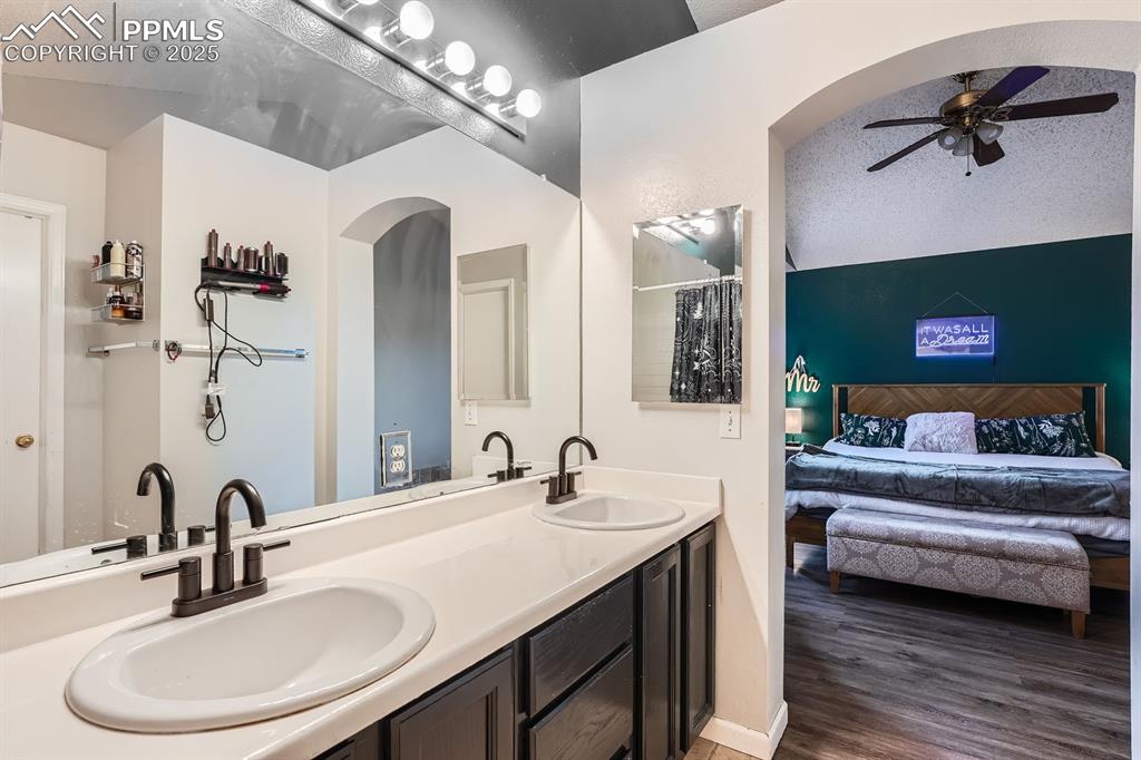 Image 13 of 28: Ensuite bathroom with a ceiling fan, double vanity, and wood finished floor