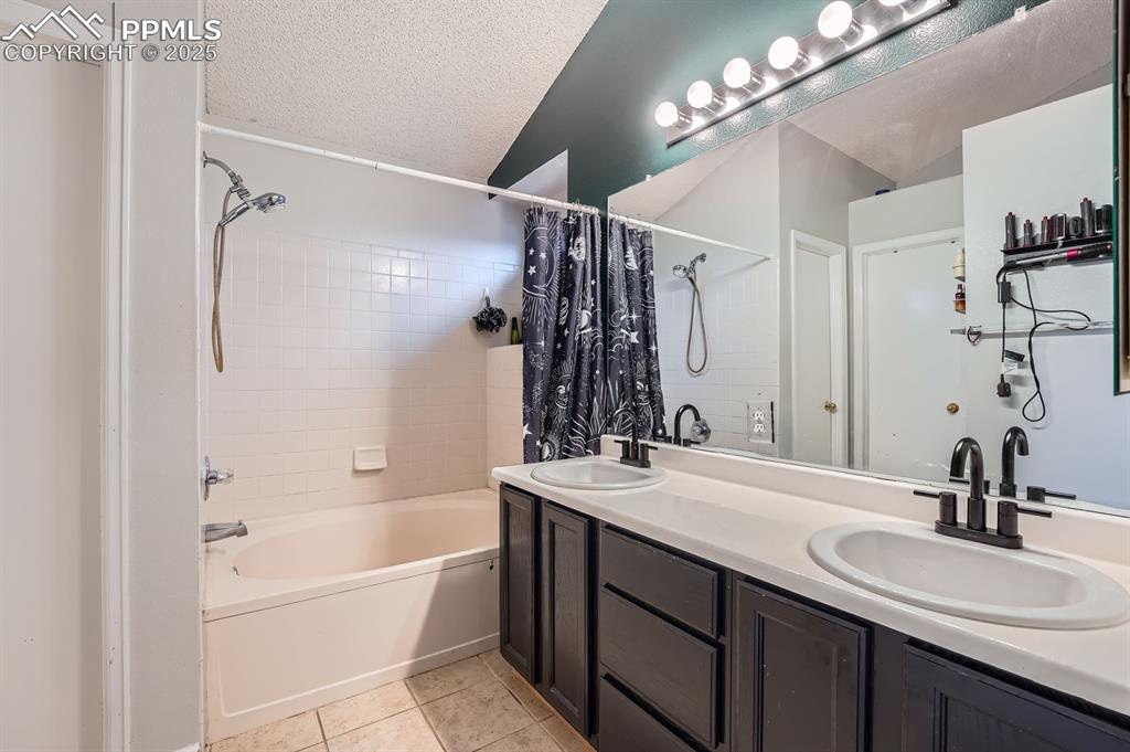Image 14 of 28: Full bathroom featuring shower / bath combo with shower curtain, double van