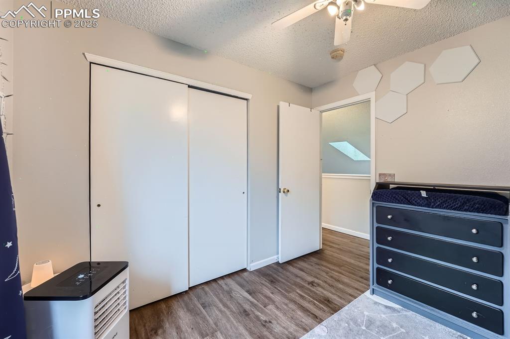 Image 16 of 28: Bedroom featuring wood finished floors, a textured ceiling, a closet, and c