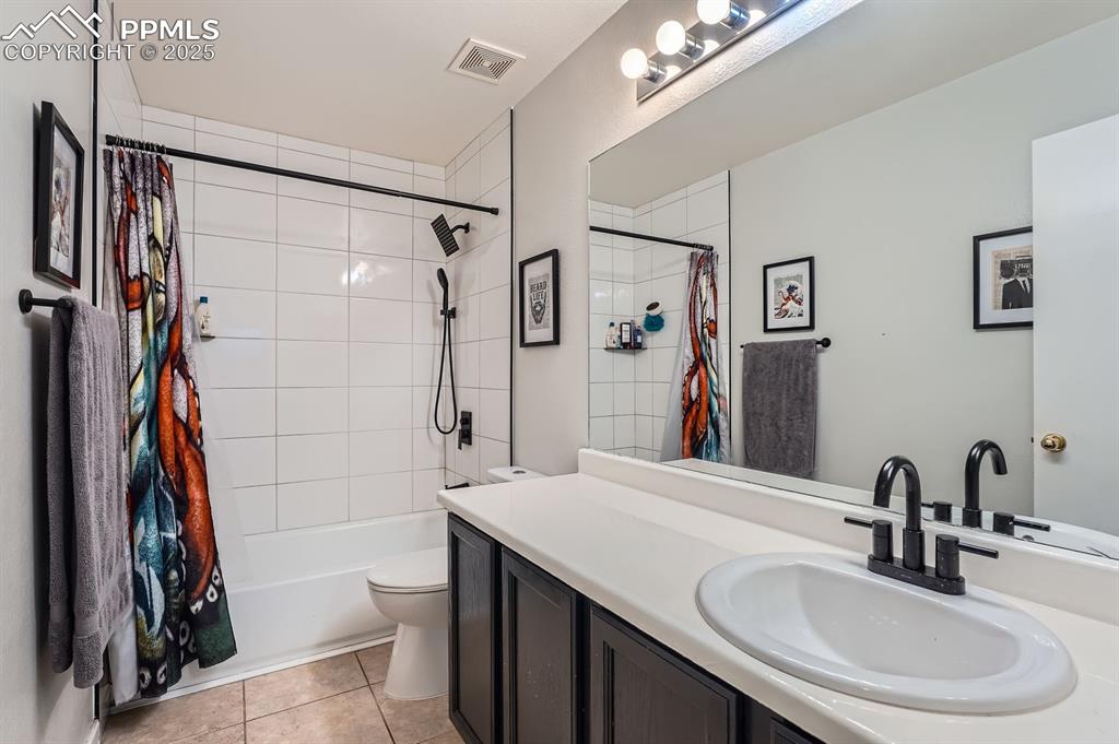 Image 17 of 28: Full bathroom with vanity, shower / bath combo, and tile patterned floors