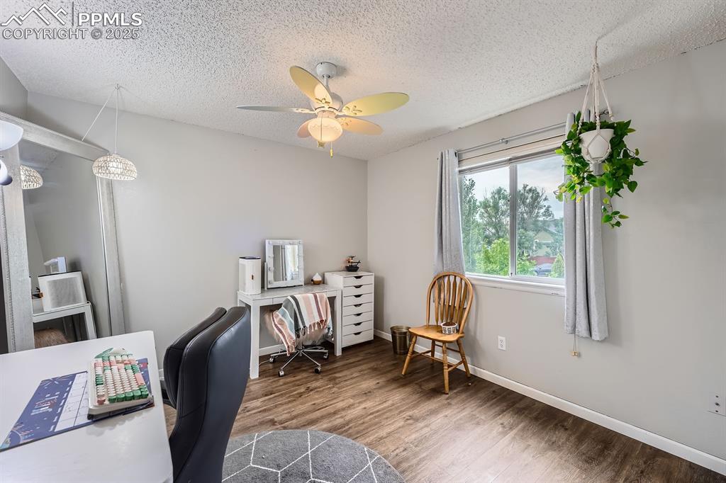 Image 18 of 28: Home office with wood finished floors, a textured ceiling, and ceiling fan
