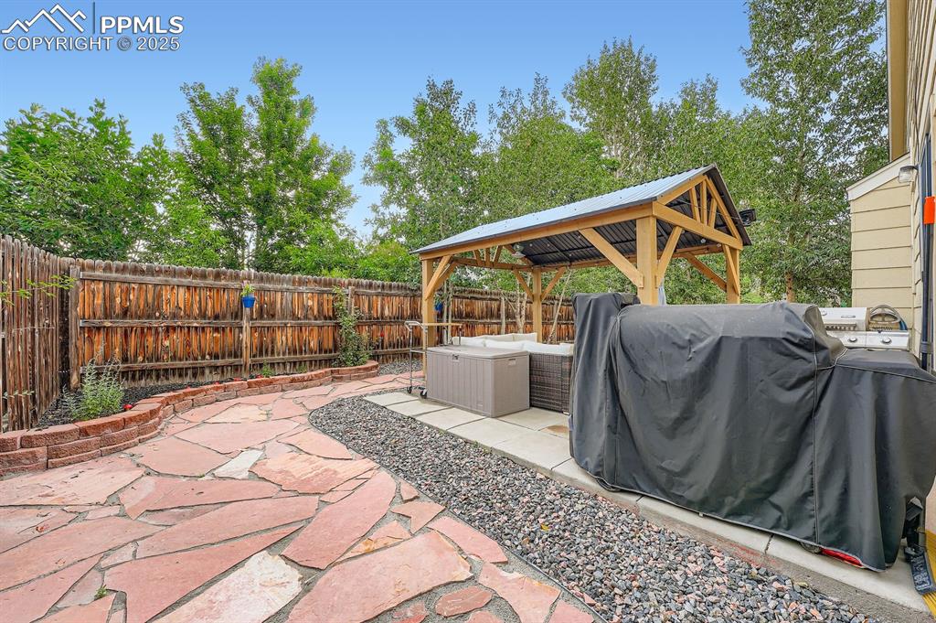 Image 26 of 28: Fenced backyard featuring outdoor lounge area, a gazebo, area for grilling,