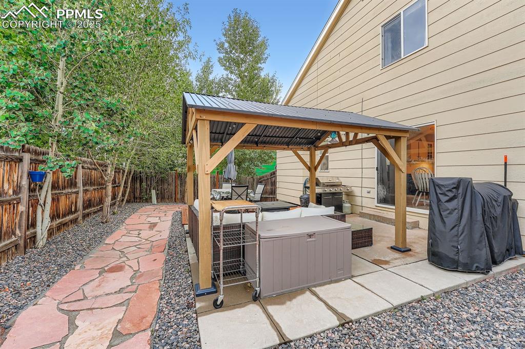 Image 27 of 28: Fenced backyard with a gazebo, area for grilling, and a patio
