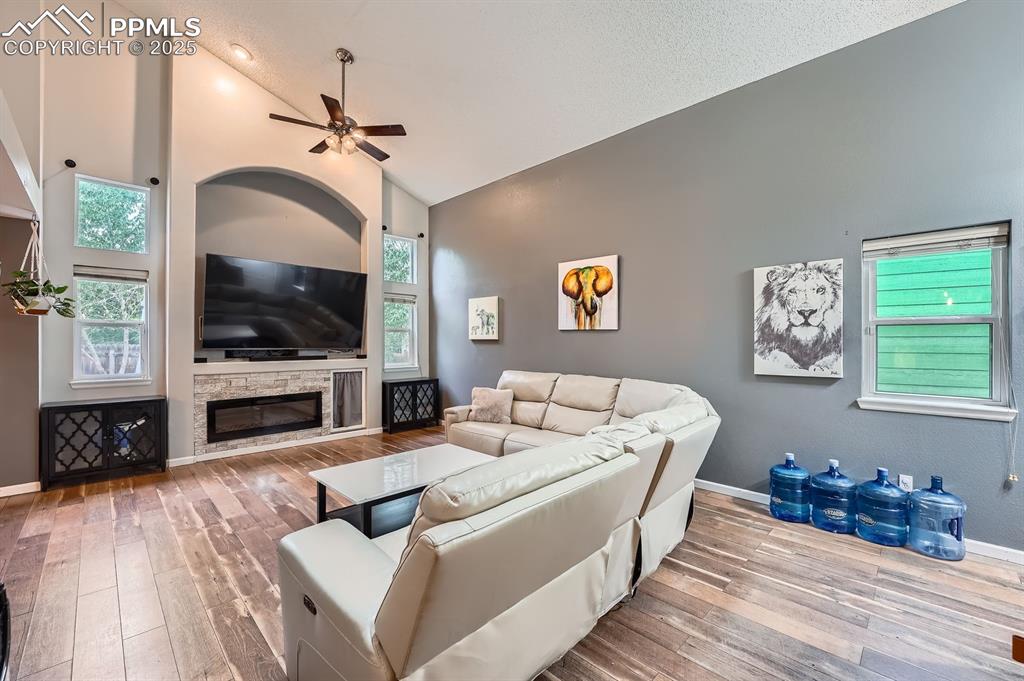 Image 4 of 28: Living area featuring high vaulted ceiling, wood-type flooring, ceiling fan