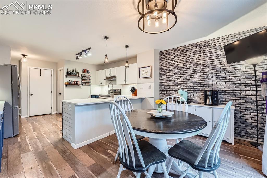 Image 6 of 28: Dining space with brick wall and wood finished floors