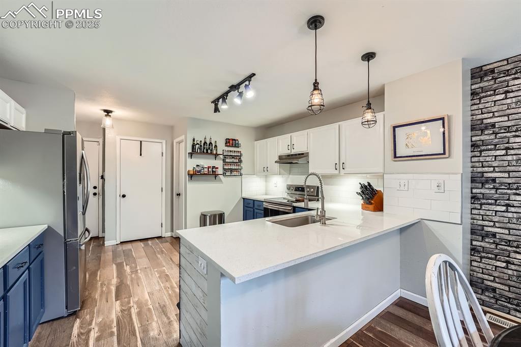 Image 7 of 28: Kitchen with blue cabinets, stainless steel appliances, light wood finished