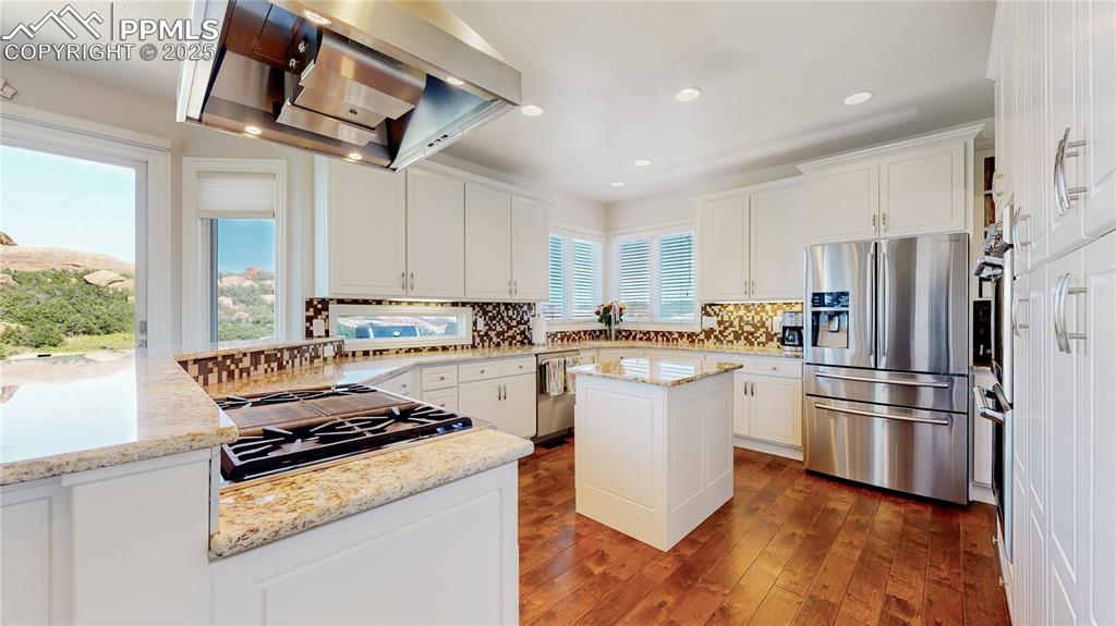 Image 13 of 46: Kitchen with wall chimney exhaust hood, stainless steel appliances, tastefu