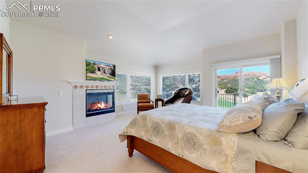 Image 14 of 46: Bedroom with light carpet, access to exterior, a fireplace, and recessed li