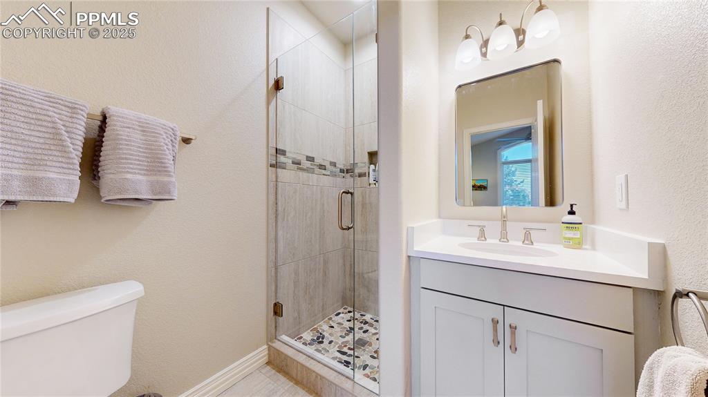 Image 20 of 46: Bathroom with a textured wall, vanity, and a stall shower