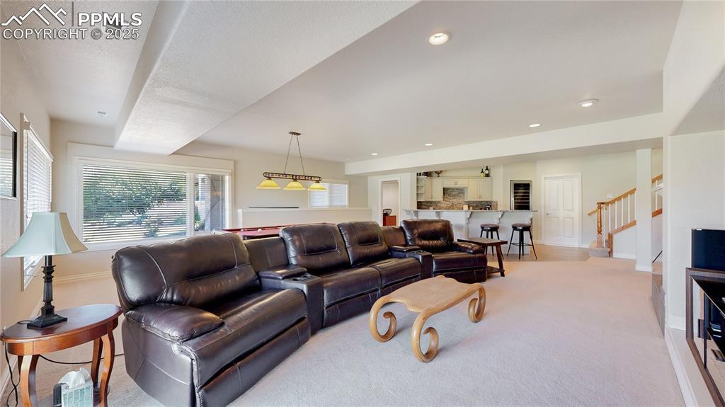 Image 24 of 46: Living room with light carpet, recessed lighting, and stairs